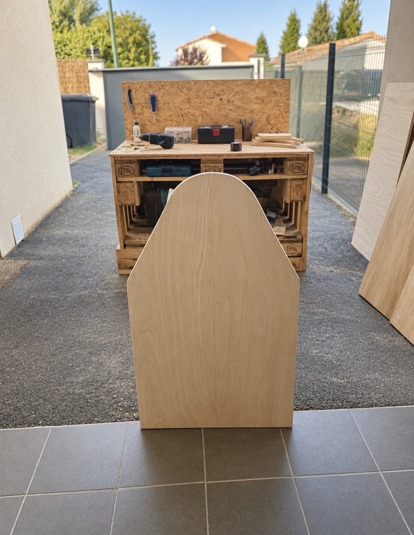 Panneau latéral en bois découpé devant l'établi extérieur